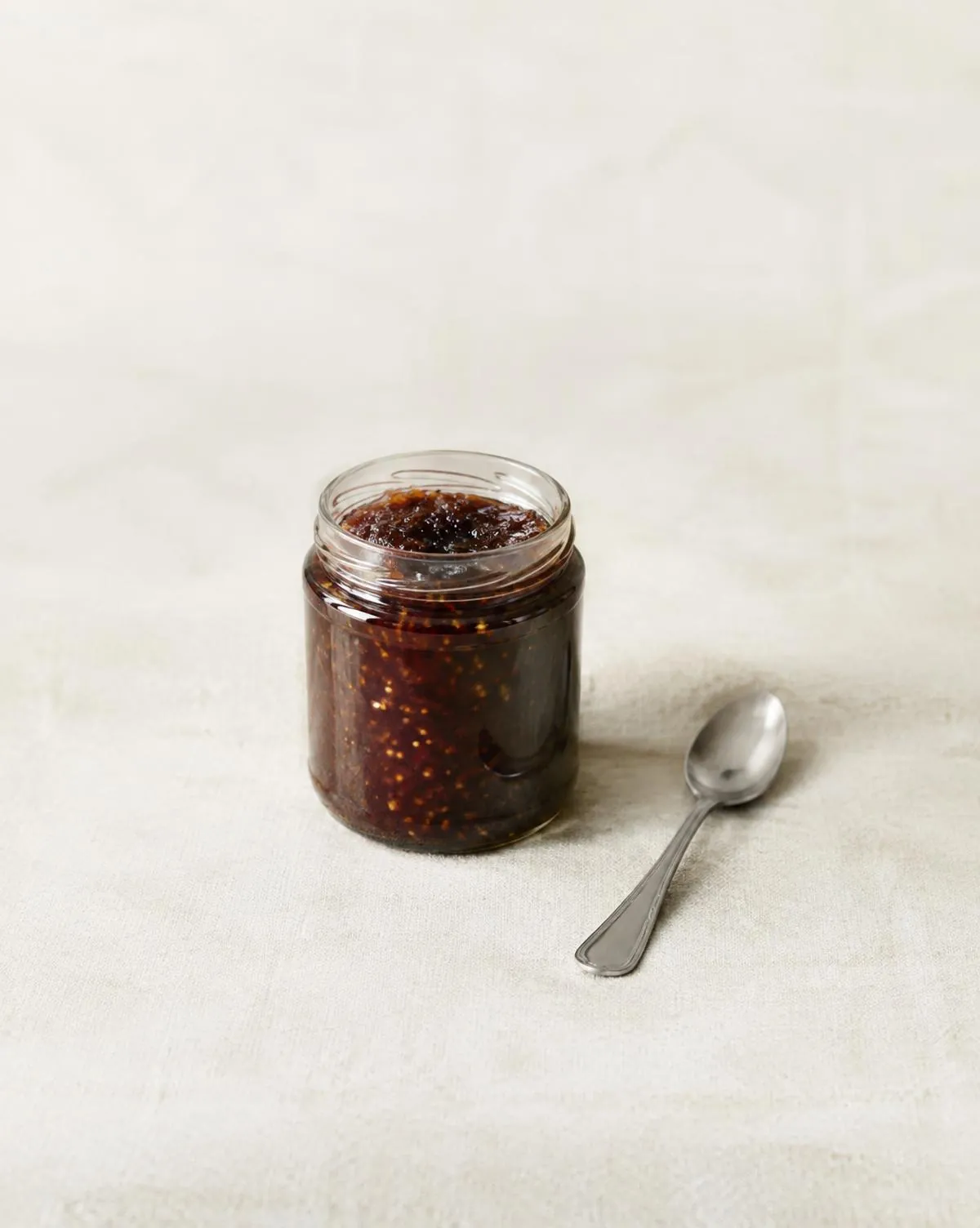 Pot de confiture de figues et cuillère sur du lin